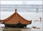  ?? CHINATOPIX ?? On July 8, residents swim to a riverside pavilion submerged by the flooded Yangtze River in Wuhan in central China’s Hubei province.