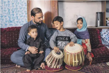  ?? Asmaa Waguih ?? Ashraf Omary, a musician who lives on Kharabat Street, with his children. He is looking for any work he can find