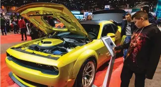  ?? TYLER LARIVIERE/SUN-TIMES FILES ?? A 2020 Chicago Auto Show attendee looks over a Dodge Challenger.