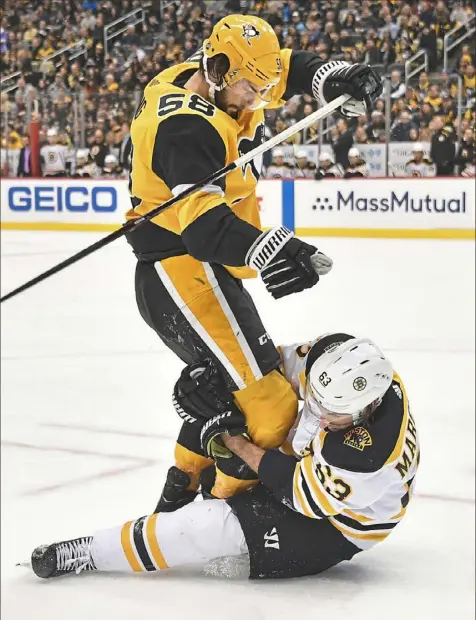  ?? Peter Diana/Post-Gazette photos ?? Bruins left winger Brad Marchand tries to take down Penguins defenseman Kris Letang Sunday at PPG Paints Arena. “Good teams don’t get discourage­d,” Letang said of the Penguins’ slow start. “They stay the course.”