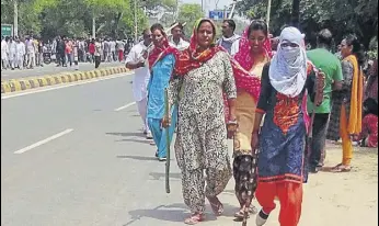  ?? HT PHOTOS ?? Women followers of Dera Sacha Sauda gathered near the court complex in Sirsa on Saturday; (right) sand bags being stacked to set up a security post at the police station.