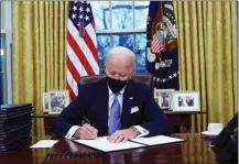  ??  ?? Undoing Trump: Biden signs executive orders on his first day.