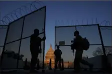  ?? Carolyn Kaster/Associated Press ?? A National Guard member opens a gate in the razor wiretopped perimeter fence around the Capitol to allow another member in at sunrise in Washington on Monday.