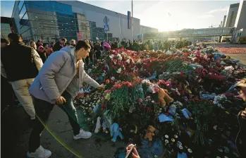  ?? ALEXANDER ZEMLYANICH­ENKO/AP ?? Mourners place flowers at a memorial Monday near Crocus City Hall on the western outskirts of Moscow. The four men charged with the massacre have been identified by the Russian government as citizens of Tajikistan.
