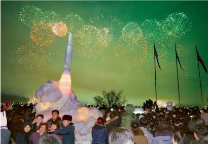  ?? AFP ?? Fireworks are seen above the Taedong River during New Year celebratio­ns as visitors pose for a photo in front of an ice sculpture of an interconti­nental ballistic missile at the Ice Sculpture Festival at Kim Il Sung Square in Pyongyang.—