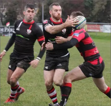  ??  ?? Enniscorth­y’s Hugh O’Neill gets his pass away as Craig Stronge (Tullamore) tackles.