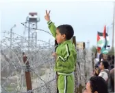  ??  ?? Un enfant palestinie­n faisant le signe de la victoire devant les barbelés de la frontière séparant la bande de Gaza avec Israël