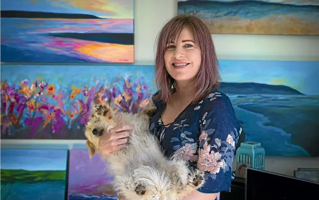  ?? MURRAY WILSON/STUFF ?? Foxton Beach artist Kylie Wardlaw, with her Foxton Estuary-loving dog Tess, in front of Wardlaw’s artworks.