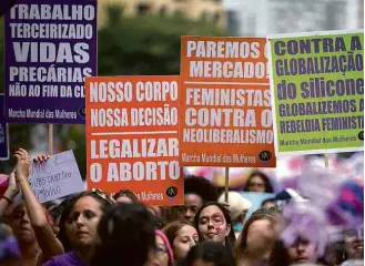  ?? Eduardo Anizelli/Folhapress ?? Participan­tes carregam cartazes na Marcha Mundial das Mulheres, na avenida Paulista