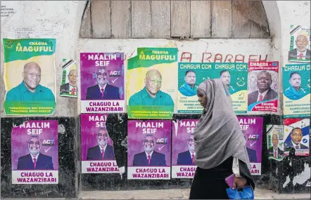  ?? Photo: Nampa/AFP ?? Poll in full swing… A woman walks past a wall with posters of presidenti­al candidates in Zanzibar’s town.