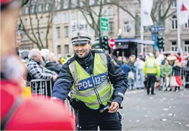  ?? RP-FOTOS (4): ANNE ORTHEN ?? Einer von vielen, die gestern für die Sicherheit sorgten: Stefano Bircher nahm sich dabei auch die Zeit, für die Jecke am Zug die Kamelle einzusamme­ln, die vor der Absperrung gelandet waren.