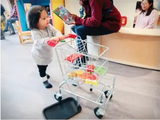  ??  ?? Eighteen-month-old Mollie Bowen pushes a pint-size shopping cart around Jabberwock­y.