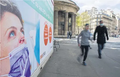  ?? BLOOMBERG ?? Pedestrian­s pass a hoarding near a Covid-19 rapid testing tent in Paris, France, on Wednesday. Yesterday’s number of confirmed cases in the coronaviru­s outbreak in France stood at 5.13 million with 99,294 deaths.