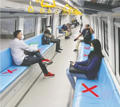  ?? ABDUL QODIR / AFP ?? Commuters sit on designated areas decided by red cross marks to ensure social distancing
on an LRT train in Palembang, South Sumatra, in Indonesia on Friday.