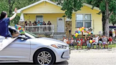  ?? STAFF PHOTOS BY ROBIN RUDD ?? East Lake Elementary teacher Rachel Hoefflin waves as she leans out of her car as it passes students and their families on 14th Avenue. On what would have been the last day of school, East Lake Elementary School teachers held a parade and drove by student houses in the East Lake community Friday.