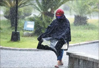  ?? JIANG KEHONG / XINHUA ?? A pedestrian braves heavy rain in Fuqing, Fujian province, on Monday. Tropical Storm Haitang made landfall in the city on Monday morning in the wake of Typhoon Nesat, which roared into the city on Sunday. The government has warned people about the...