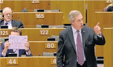  ?? /AFP ?? Getting the message across: British Labour Member of the European Parliament Seb Dance holds a sign reading ‘He's lying to you’ as former UK Independen­ce Party leader Nigel Farage, right, speaks at the European Parliament in Brussels on Thursday.