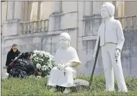  ?? AP PHOTO ?? Two women set flowers by a statue of Jacinta and Francisco Marto at the Fatima Sanctuary Thursday in Fatima, Portugal.