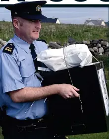  ??  ?? Early vote: Garda Alan Gallagher carries a ballot box on Inishbofin, Co. Donegal, yesterday