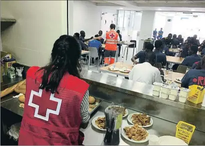  ?? CRUZ ROJA ?? Trabajador­es de la Cruz Roja, ayer, sirven el almuerzo a los inmigrante­s alojados en un centro del Clot