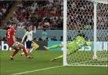  ?? FRANK AUGSTEIN — THE ASSOCIATED PRESS ?? England's Phil Foden, center, scores past Wales' goalkeeper Danny Ward, right, during a World Cup group B match at the Ahmad Bin Ali Stadium in Al Rayyan, Qatar, on Tuesday.