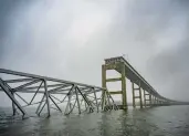  ?? JERRY JACKSON/STAFF ?? A collapsed section of the Francis Scott Key Bridge is seen in the fog on the southwest side of the Patapsco River. On March 26, the container ship Dali hit a structural pier causing a subsequent collapse.