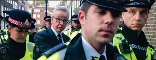  ??  ?? PROTECTION: Officers form a close circle around Michael Gove. Right: Jacob Rees-Mogg and his son Peter, 12, are escorted home by police