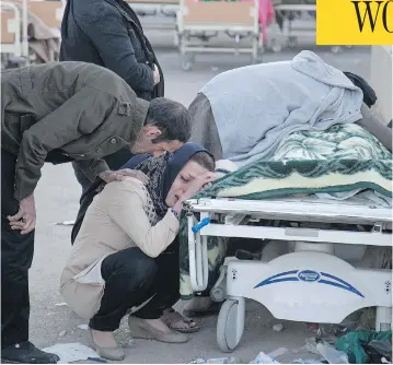  ?? FARZAD MENATI / TASNIM NEWS AGENCY VIA AP ?? Relatives weep over the body of an earthquake victim in Sarpol-e-Zahab, western Iran on Monday. A 7.3 magnitude earthquake struck the Iran-Iraq border region on Sunday night, toppling buildings and killing hundreds.