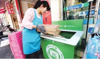  ?? PROVIDED TO CHINA DAILY ?? A woman drops empty delivery boxes into a community recycling bin in Kunming, Yunnan province, in 2018.