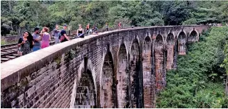  ??  ?? Tourists enjoying the scenic view from the famous Nine Arches Bridge in Demodara, Ella Pic by Pradeep Pathirana