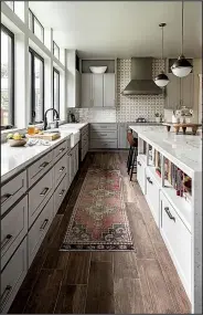  ?? AP/Grace Laird Photograph­y/Moore House Interiors ?? Interior designer Ashley Moore used a vintage Moroccan rug to add warmth and color to this kitchen. The rug’s appealingl­y worn look blends with the reclaimed wood floor.