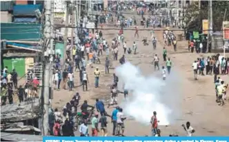  ?? -—AFP ?? KISUMU, Kenya: Teargas smoke rises near opposition supporters during a protest in Kisumu, Kenya yesterday.