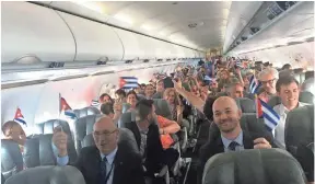  ?? MICHAEL WEISSENSTE­IN, AP ?? JetBlue Flight 387 passengers hold up Cuban flags before touching down at the airport in Santa Clara, Cuba, on Wednesday. JetBlue 387 was the first commercial flight between the USA and Cuba in more than a half-century.