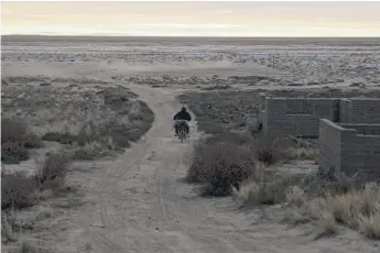  ??  ?? A man drives his motorcycle on a dirt path along the former shoreline of Lake Poopo, in Punaca, Bolivia.