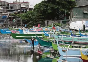  ??  ?? Halted: A man walks by docked fishing boats in the city of Navotas in the Philippine­s. The Philippine economy was one of Asia’s fastest growing before the pandemic but is now on the brink of recession.