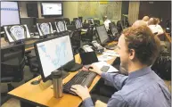  ??  ?? City employees and emergency personnel work in front of computer monitors during the emergency exercise.