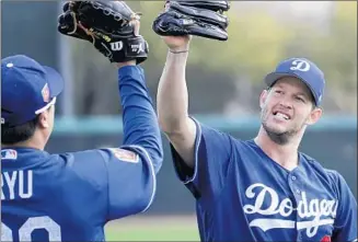  ?? Robert Gauthier Los Angeles Times ?? CLAYTON KERSHAW, who has an opt-out clause in his contract that he could execute after this season, high-fives fellow Dodgers starting pitcher Hyun-Jin Ryu during a spring workout.