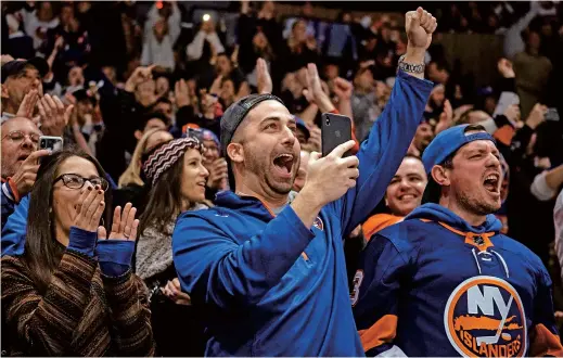  ??  ?? Fans celebrate a goal by New York Islanders’ Anders Lee during the second period of an NHL hockey game against the Columbus Blue Jackets. This season is the first of three in which the Islanders will play half its home schedule at the sleek Barclays Center in Brooklyn and the rest in the venerable Nassau Coliseum on Long Island. — IC