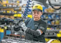  ??  ?? Margarita Cardenas attaches an engine head at the plant. The plant exports 70 percent of its engines.