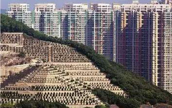  ?? AP ?? Left: Graves cover a hillside in front of apartment buildings in Hong Kong. The cramped Chinese city of 7.2 million is fast running out of space to store the dead.