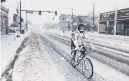  ?? MICAHEL CIAGLO/GETTY ?? A bicyclist makes his way down an icy and snowy street Sunday in Denver. The runways were closed just before noon Sunday at Denver Internatio­nal Airport.