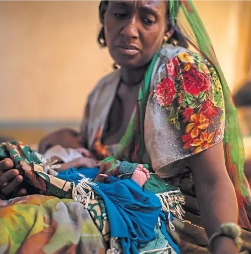  ??  ?? Abeba Gebru, 37, holds her 20-day-old daughter. She gave birth at home in the village of Getskimile­sley then walked for 12 days to get her famished baby to a clinic in the trouble-torn Tigray region