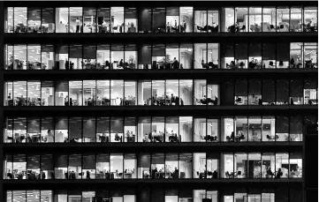  ?? — Reuters photo ?? Workers are seen in an office tower in the Canary Wharf financial district at dusk in London, Britain.