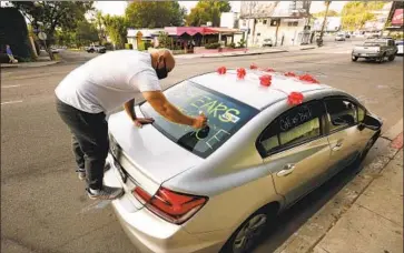  ?? Al Seib Los Angeles Times ?? WALTER ALMENDAREZ, a bellman at the Chateau Marmont for 23 years, writes messages in favor of Assembly Bill 3216 in September as hotel workers formed a caravan to Sacramento to show their support.