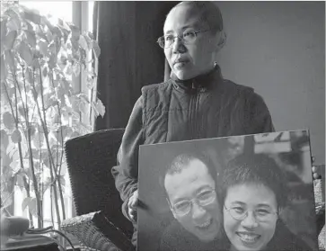  ?? Ng Han Guan Associated Press ?? LIU XIA holds a photo of her and her husband, dissident and Nobel Peace Prize laureate Liu Xiaobo. He is receiving treatment at a hospital in northeaste­rn China; she has been under house arrest since his detention.