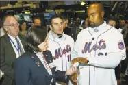 ?? Mel Nudelman / Associated Press ?? New York Mets first baseman Carlos Delgado, right, gives a signed baseball to Angela Roman of Merrill Lynch, as catcher Paul Lo Duca, center, and Mets vice president of media relations Jay Horwitz look on during a tour of the stock exchange floor in 2006.