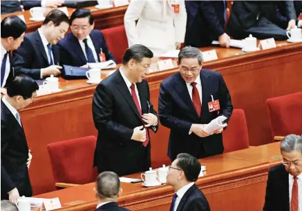  ?? ?? Ο πρωθυπουργ­ός Λι Τσιάνγκ (δεξιά) με τον πρόεδρο της Κίνας Σι Τζινπίνγκ στη σύνοδο, λίγο πριν από την ομιλία του. Σε μια ένδειξη σκλήρυνσης της στάσης του Πεκίνου έναντι της Ταϊβάν, ο Λι απέφυγε τη στερεότυπη αναφορά στην «ειρηνική ενοποίηση» της νήσου με την Κίνα. Μίλησε για αύξηση 8% των αμυντικών δαπανών και στόχο ανάπτυξης 5% με μοχλό την εγχώρια ζήτηση, χωρίς ωστόσο να δώσει κίνητρα.