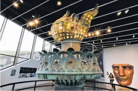  ??  ?? The original torch and flame and full-scale face model are displayed in the new 26,000-square-foot Statue of Liberty Museum.