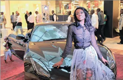  ?? PICTURE: ANTOINE DE RAS ?? Top model Joelle Kayembe, the winner of the most stylish model at the SA Style Awards, sits in front of the latest F-Type Jaguar Coupe at the launch of the Hyde Park Haute Couture Centre. In the background is young Libo Matai, having a close look at...