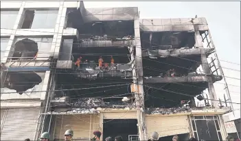  ?? ?? kational Disaster Response Force members and firefighte­rs inspect a commercial building a day after a fire broke out in kew Delhi. — AFP photo